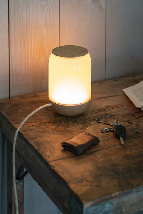 lampe à poser qui imitte la lumiere de l'aube du soleil sur un meuble ancien dans un environnment d'entré pour poser ses clé et son porte monnaie